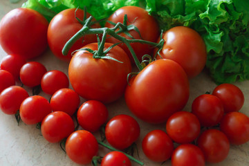 Large and small red tomatoes along with lettuce leaves.