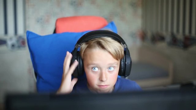 Teenage blond boy playing computer games on PC