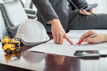 Architect and construction engineer or surveyor discussion plans in office