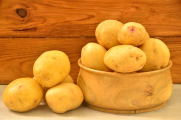 Potatoes in a bowl and heap on the background of wooden boards