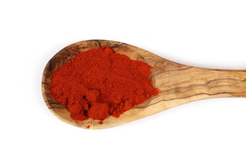 Pile of red paprika powder in wooden spoon isolated on white, top view