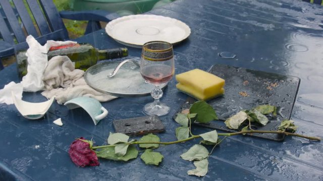 Uncleared plastic table after party under pouring rain