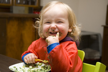 Mädchen hat das Gesicht voller Spinat