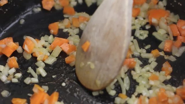 Stirring carrots, onions, and garlic on a pan