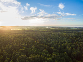 Fototapeta na wymiar Aerial view of a beautiful sunset over forest landscape with green fields