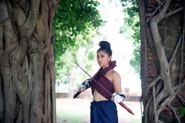 Pretty Asian woman posing in Thai ancient warriors at Gate of time of Wat Phra Ngam in Ayutthaya Historical Park ,Thailand.