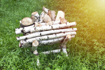 Birch firewood on a stand on the grass on a sunny day