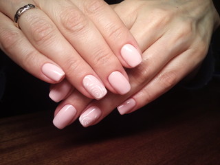 The manicurist excellently made her work a beautiful manicure with a polish gel on her hands and the client is happy
