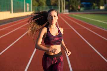 Professional sportswoman athlete sprinter running on stadium track in evening. Healthy lifestyle...