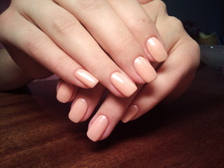 The manicurist excellently made her work a beautiful manicure with a polish gel on her hands and the client is happy