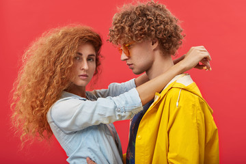 Obraz premium People, love, affection, dating, romance, relationships and happiness concept. Romantic sweet beautiful European couple with ginger curly hair wearing stylish clothes hugging or dancing indoors