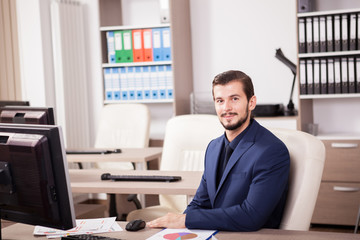 Naklejka premium Young Businessman in suit working in his office. Business and corporate. Image of young succesful entrepreneur at his work place.
