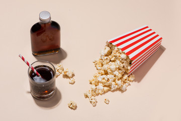 Popcorn in red and white cardboard with glass of soda