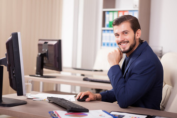 Smiling Businessman in suit working in his office. Business and corporate. Image of young succesful entrepreneur at his work place.