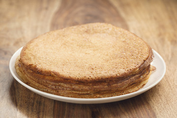 homemade blini stack on plate on wood table