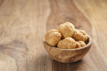 profiteroles in olive bowl on wooden table