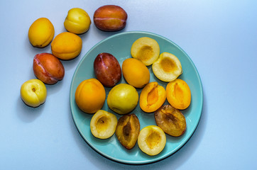 Summer fruits: apples, pears, apricots, plums on a blue plate