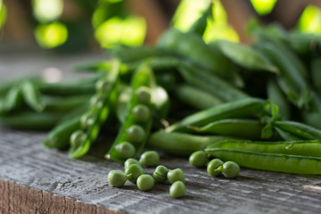 pods of young green juicy peas in the gazebo on a wooden bench in summer