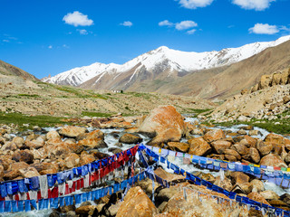 Buddhist prayer flags over the small river with blue sky and mountain on background in india