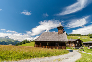 historic wooden church in a small alpine village in Switzerland with a gravel road leading up to it