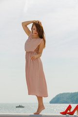Fototapeta na wymiar Woman wearing long light pink dress on jetty