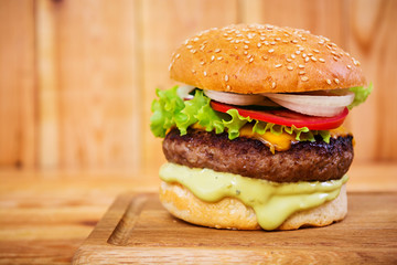 Delicious handmade burger on wooden background. Close view