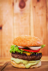Delicious handmade burger on wooden background. Close view