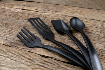 black plastic kitchen set skimmer, spade of frying pan on wooden