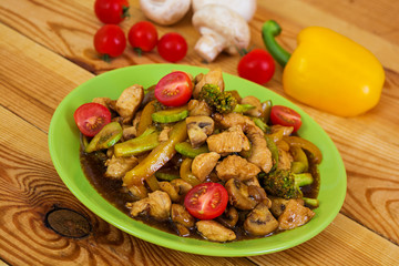 Stir fry chicken, zucchini and broccoli on wooden background