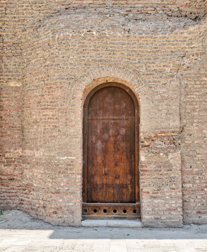 Grunge wooden aged vaulted door on exterior stone bricks wall of Amr Ibn Al-As, Medieval Cairo, Egypt