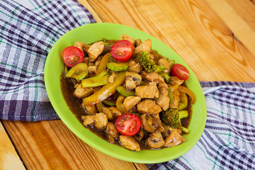 Stir fry chicken, zucchini and broccoli on wooden background