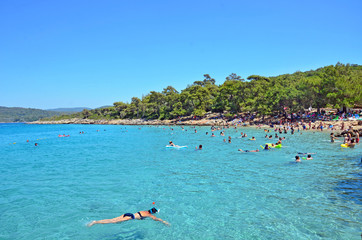 People are swimming in a turquoise sea in Incekum Beach, Marmaris.