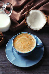 Cup with drink and ingredients for coconut coffee on wooden table