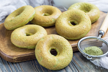 Fresh baked matcha banana donuts on wooden board and table, horizontal