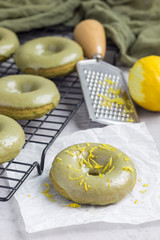 Freshly baked matcha banana donuts with matcha citrus glaze, on cooling rack and wooden table