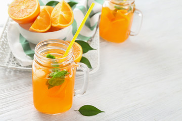 Mason jar of fresh orange lemonade on wooden background