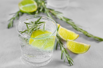 Glass of fresh lime lemonade with rosemary on grey background