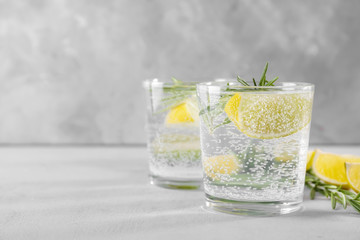 Glass of fresh lemonade with rosemary on grey background