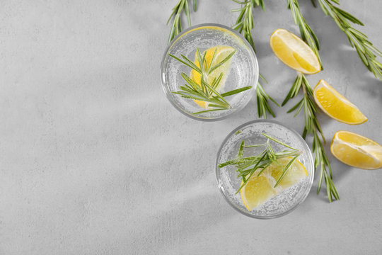 Glasses of fresh lemonade with rosemary on grey background