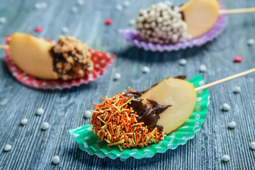 Tasty pieces of candied apple on wooden table, closeup