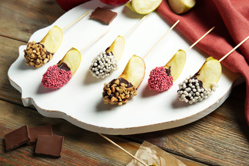Stand with pieces of candied apple on wooden table, closeup