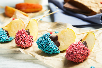 Parchment with pieces of candied apple on wooden table, closeup