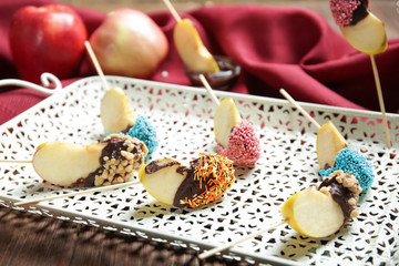 Tray with pieces of candied apple on wooden table, closeup
