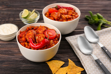 Two bowls with delicious chili turkey on wooden table