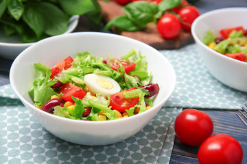Bowl of fresh vegetable salad on wooden table