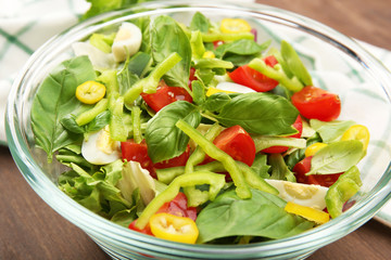 Glass bowl of fresh vegetable salad on wooden table