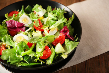 Bowl of fresh vegetable salad on wooden table