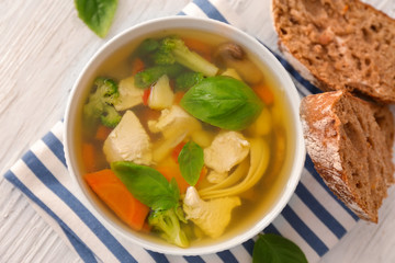 Bowl with delicious turkey soup and bread on table