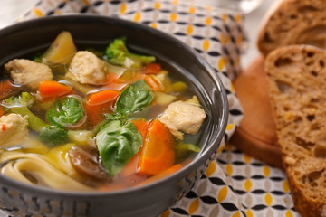 Bowl with delicious turkey soup and bread on table