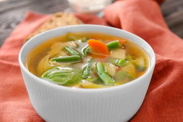 Bowl with delicious turkey soup on table, close up